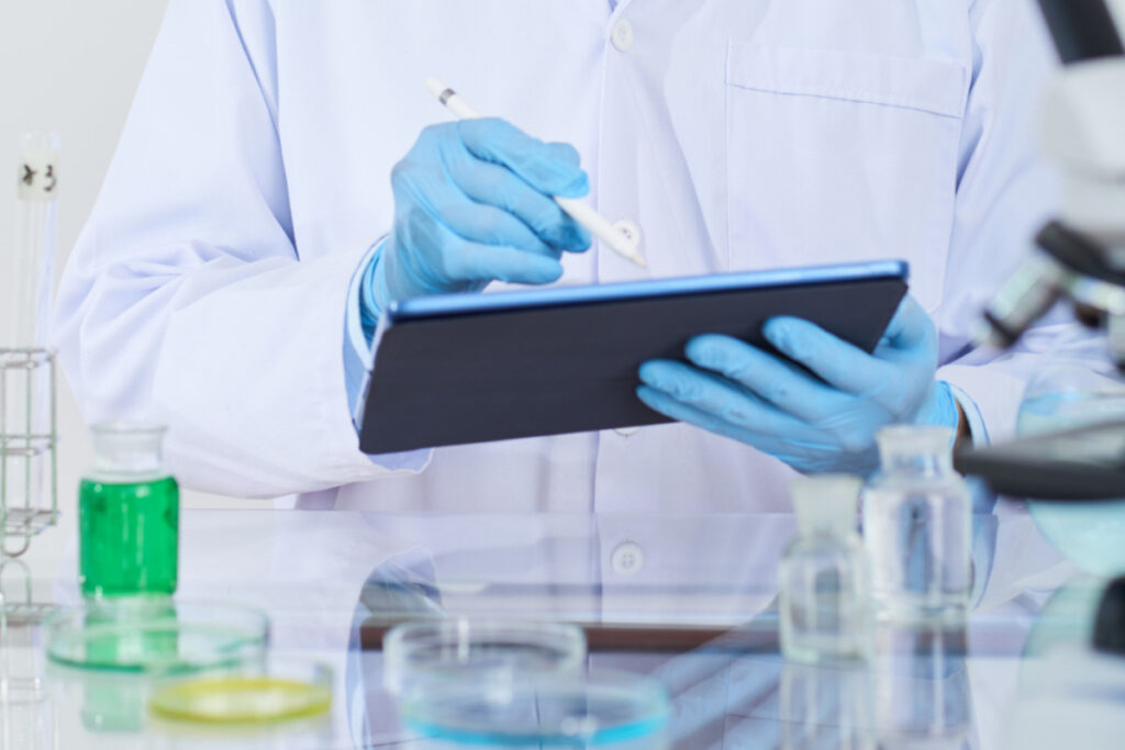 Scientist taking note on a tablet in a lab. Avoid documentation errors with good documentation practices and digital documentation.